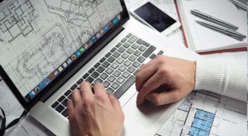 civil engineer working on laptop and blueprints